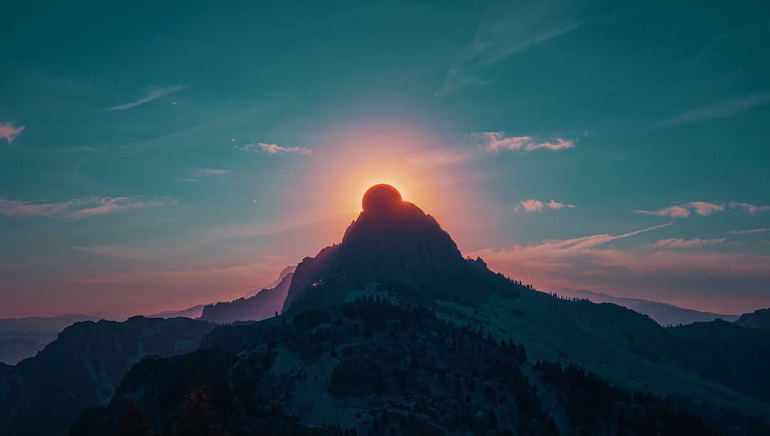 Sunrise halo crowning rugged mountain peak, creating cinematic silhouette and teal sky