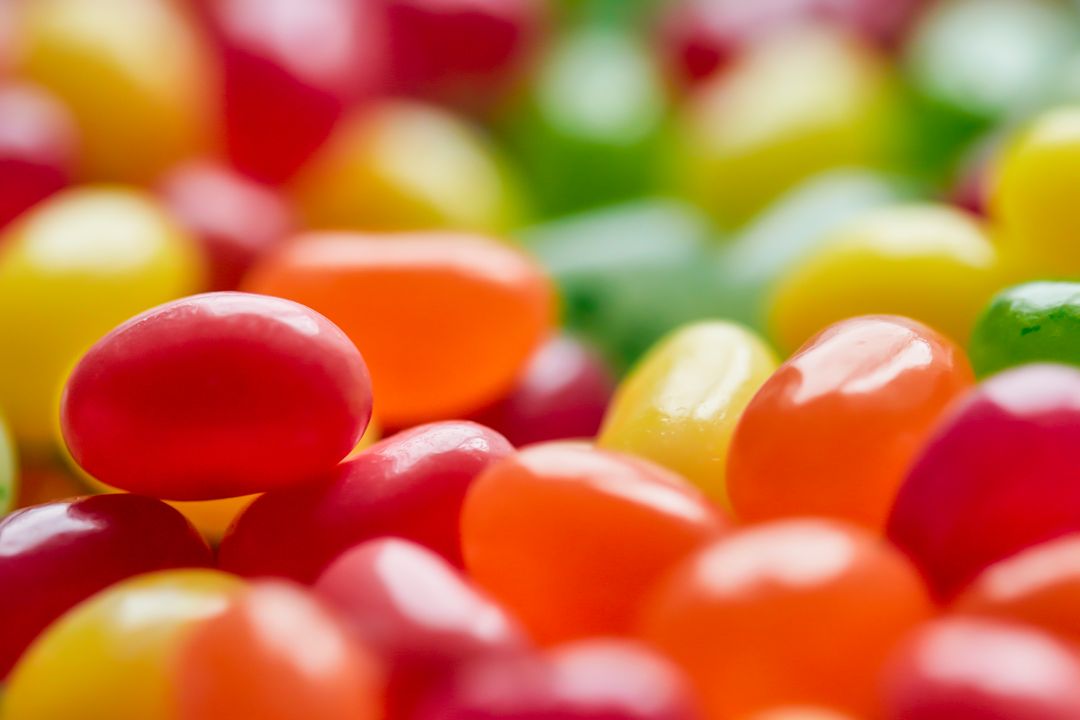 Macro close-up of colorful jelly beans with glossy shells forming vibrant candy mosaic
