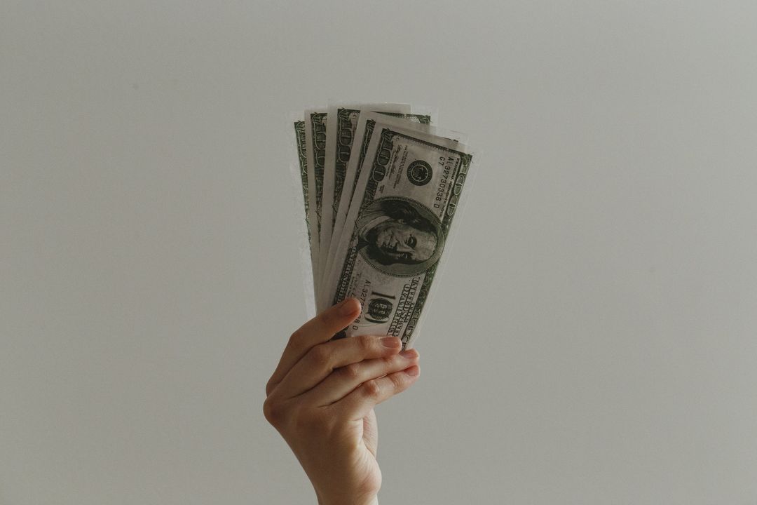 Hand Holding Fan of US Dollar Bills with Gray Background