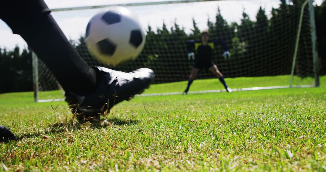 A soccer player in black cleats attempts to score against a poised goalkeeper. - Free Images, Stock Photos and Pictures on Pikwizard.com