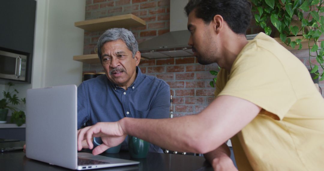 Man Helping Elderly Father with Computer in Modern Kitchen - Free Images, Stock Photos and Pictures on Pikwizard.com