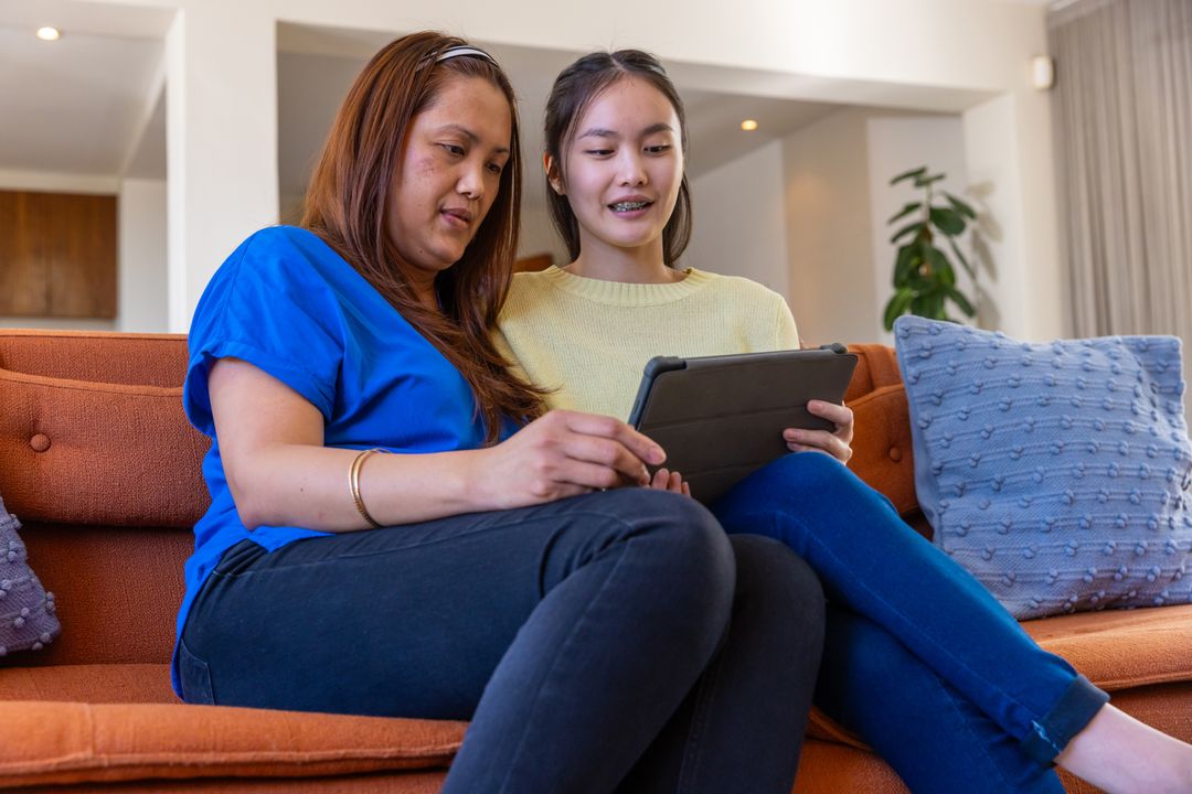 Asian Mother and Daughter Bonding While Using Tablet on Sofa