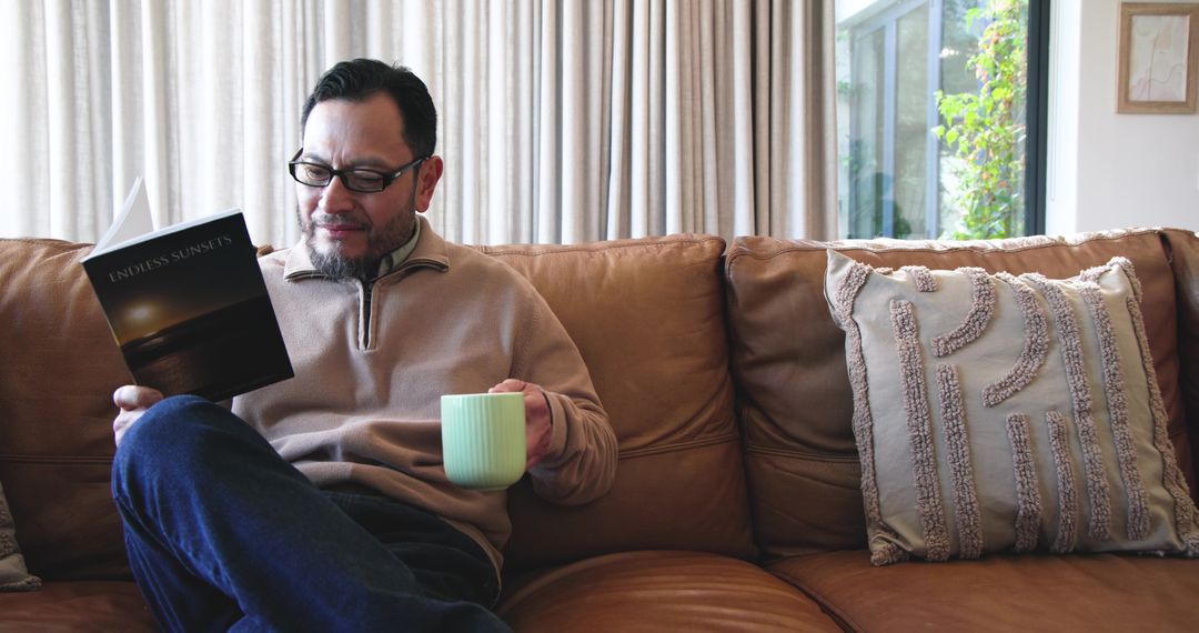 Asian Man Relaxing at Home with Book and Coffee
