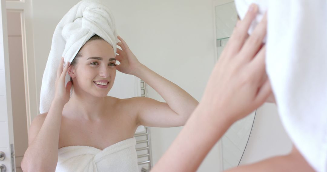 Young Woman with Towel Wrapped Hair Smiling in Bathroom Mirror - Free Images, Stock Photos and Pictures on Pikwizard.com