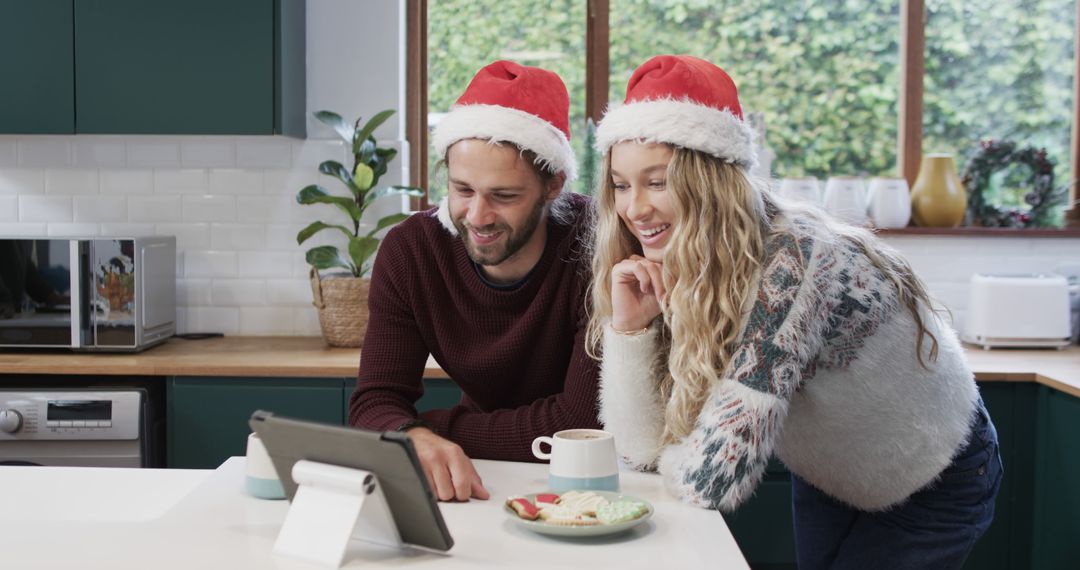 Happy Couple in Santa Hats Watching Tablet in Kitchen - Free Images, Stock Photos and Pictures on Pikwizard.com