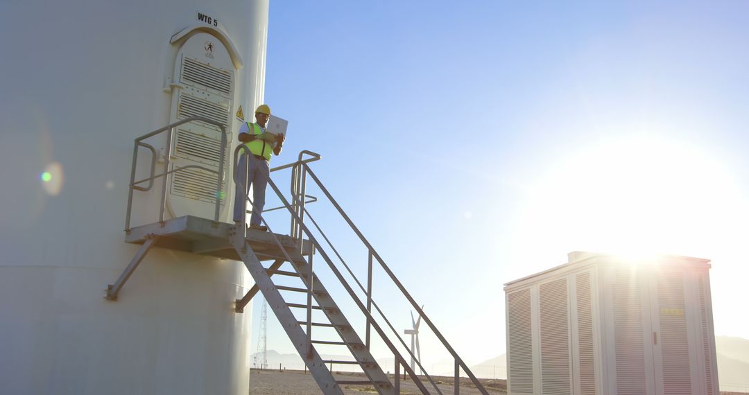 Worker Inspecting Wind Turbine Structure in Morning Sunlight - Free Images, Stock Photos and Pictures on Pikwizard.com