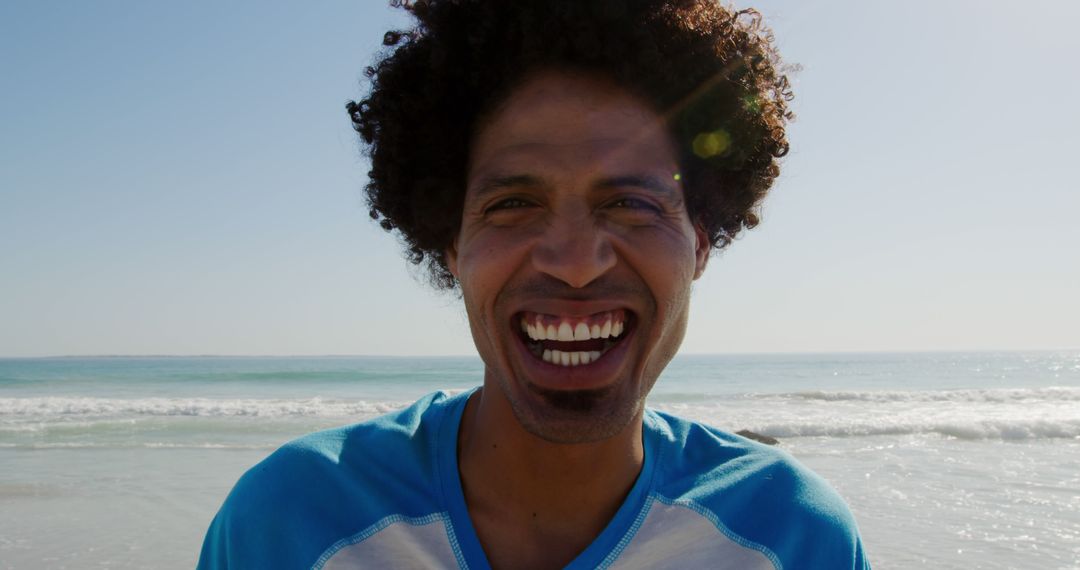 Smiling Man with Curly Hair Enjoying Beach on Sunny Day - Free Images, Stock Photos and Pictures on Pikwizard.com