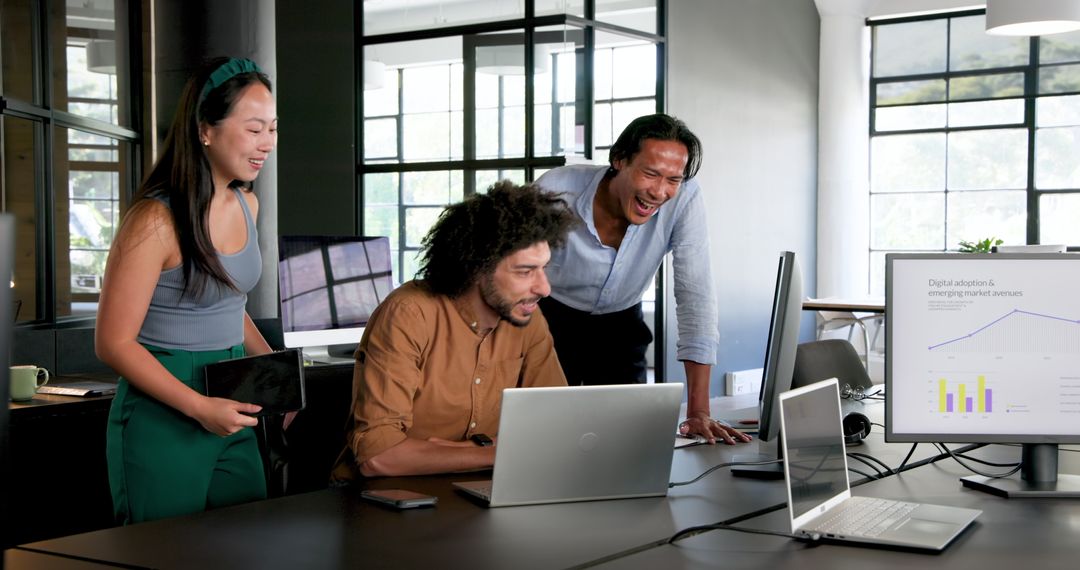 Diverse Team Collaborating in Modern Office with Laptops and Charts