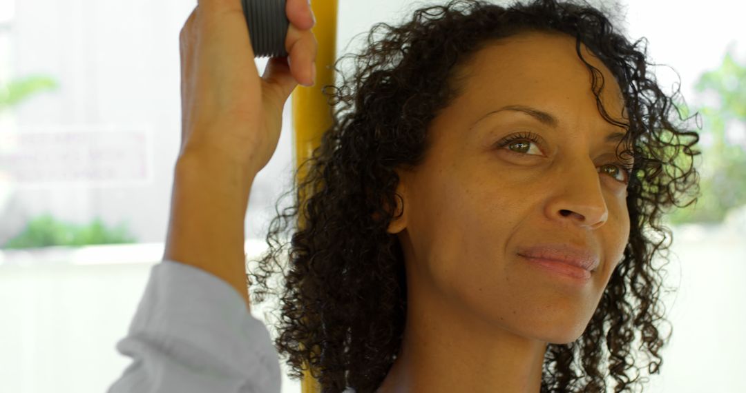 Woman with Curly Hair Commuting on Bus Standing and Holding Handrail - Free Images, Stock Photos and Pictures on Pikwizard.com