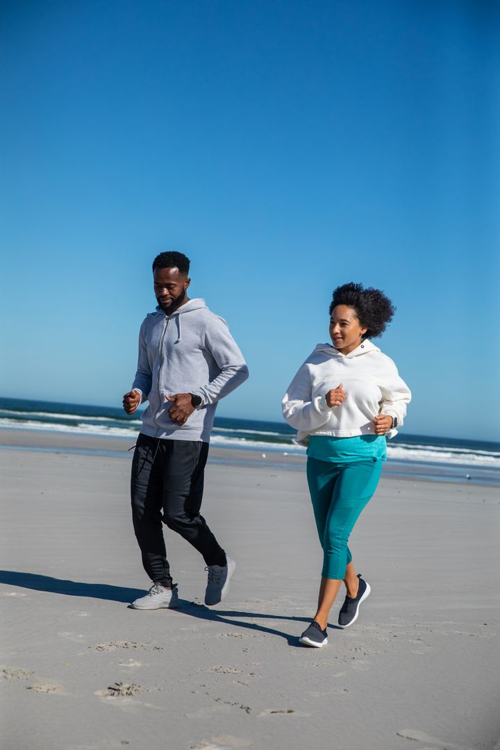 Diverse Friends Running on Sandy Beach in Stylish Activewear