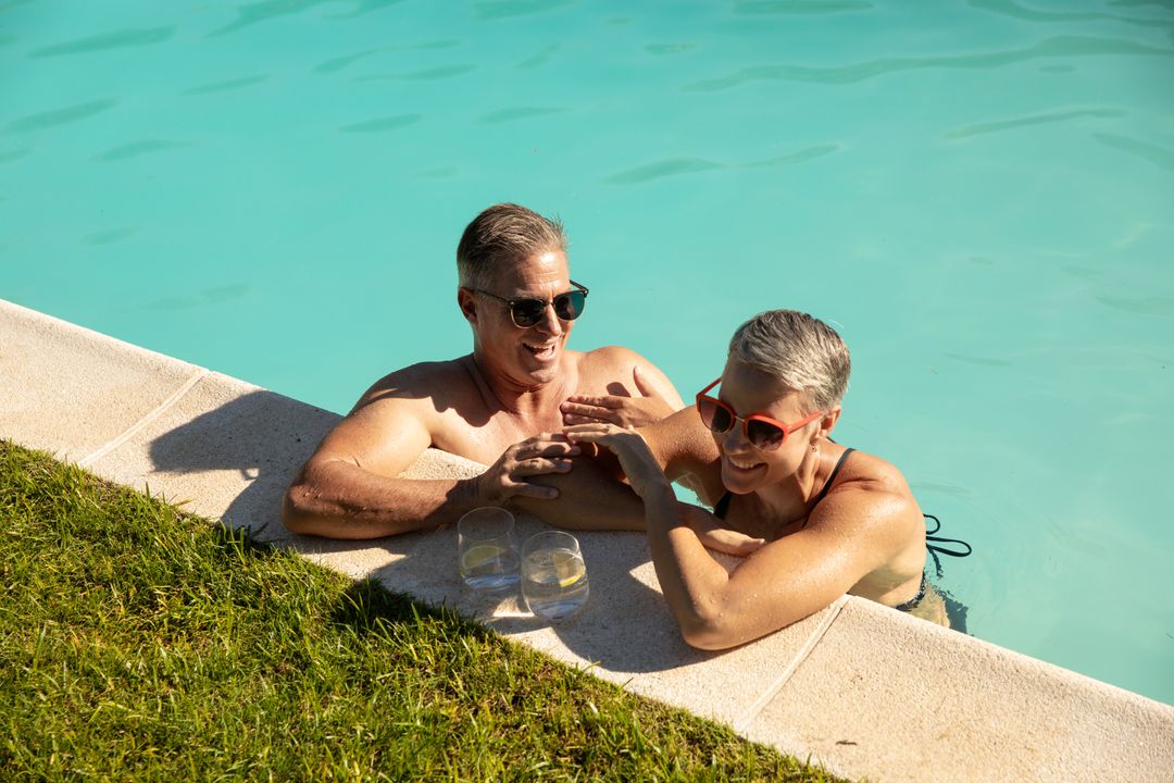 Senior Couple Relaxing in Pool Wearing Sunglasses on a Sunny Day