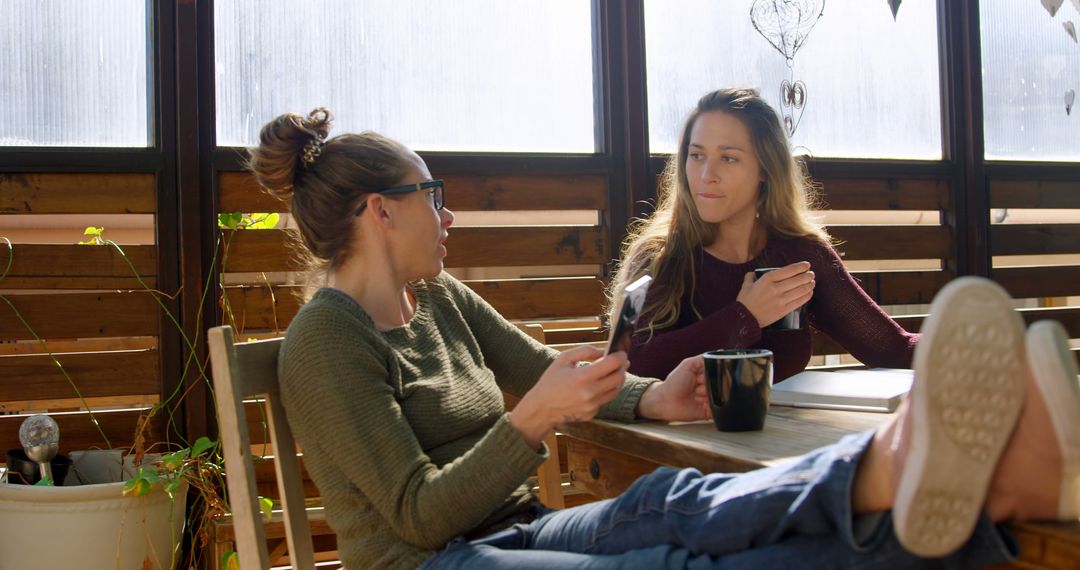 Two Women Relaxing and Conversing Over Coffee on Terrace - Free Images, Stock Photos and Pictures on Pikwizard.com