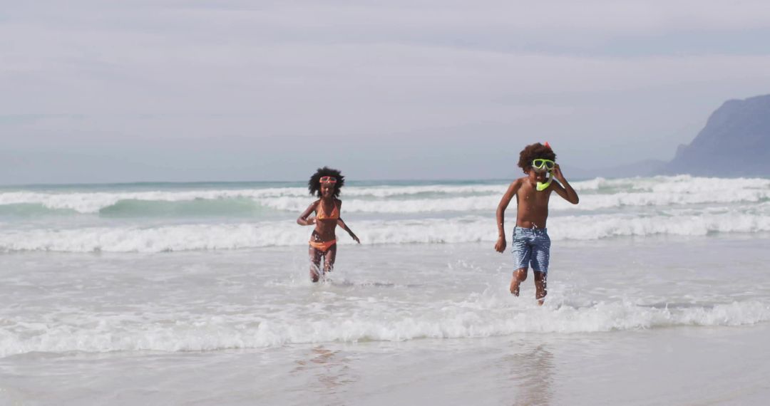 Siblings in Colorful Beachwear Running in Waves at Ocean