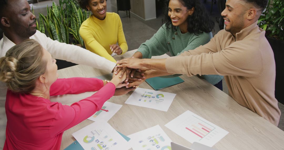 Diverse Team Celebrating Success with Group Hands in Office