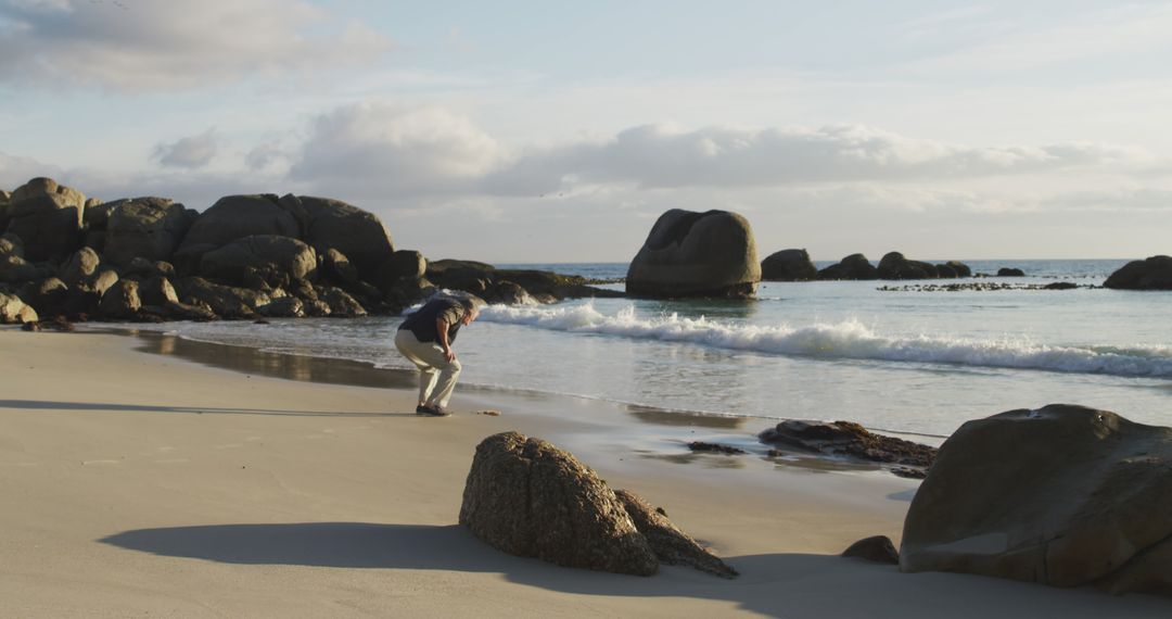 Senior Man Enjoying Quiet Beach with Rocky Coastline - Free Images, Stock Photos and Pictures on Pikwizard.com