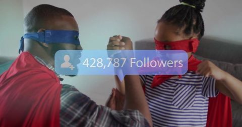 Father and Daughter in Superhero Costumes Arm Wrestling