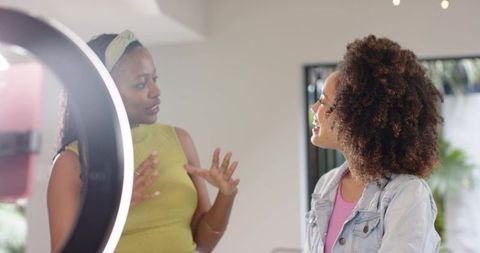 Diverse female creators collaborating in studio with ring light and casual conversation