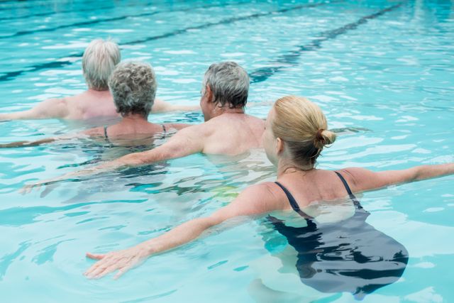 Senior adults engaging in swimming exercise in a pool. Ideal for promoting active lifestyles, fitness programs for the elderly, and aquatic therapy. Can be used in health and wellness campaigns, fitness advertisements, and senior care brochures.