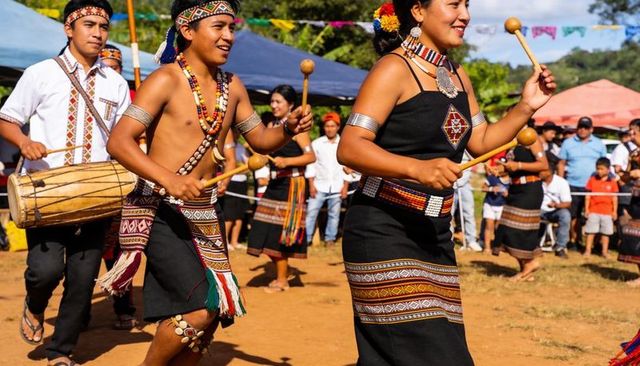 Traditional festival drum dance with woven beadwork, wooden mallets, outdoor celebration