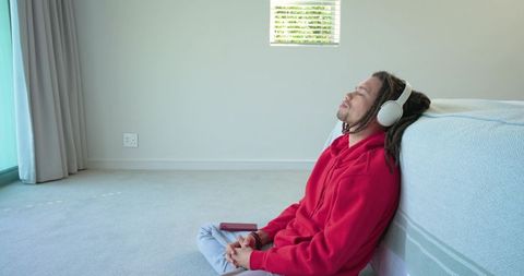 Listening to music and relaxing on floor in minimal bedroom, man with dreadlocks