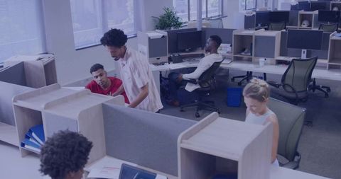 Coworkers collaborating at open-plan office workstations in natural daylight