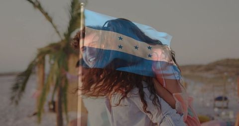 Joyful Couple Playing Piggyback Ride on Tropical Beach with Overlay Flag