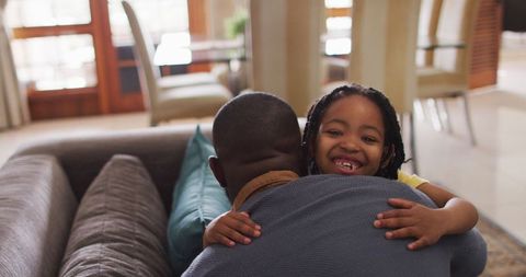 Joyful Girl Hugging Her Father on Couch