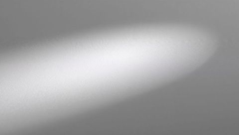 Soft oval spotlight glowing on gray fine-grain surface minimal abstract light background