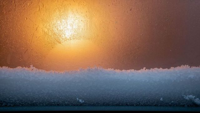 Sunlit frosted window sill with snow ridge and warm amber backlight, closeup texture