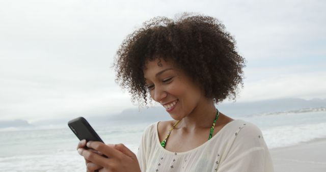 Young Woman Smiling While Using Smartphone by Ocean - Download Free Stock Images Pikwizard.com