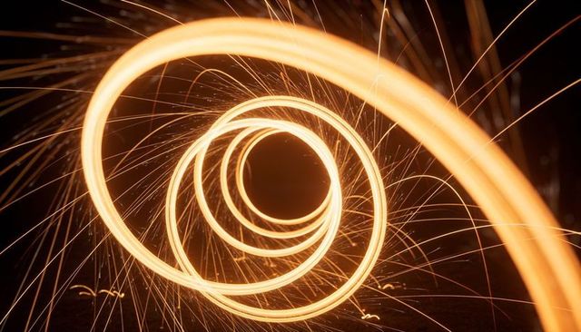 Golden spiral light painting with sparks and concentric rings creating dynamic vortex