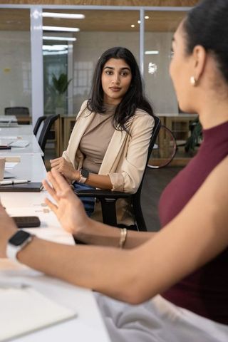 Young professional women collaborating in modern open-plan office meeting and discussion
