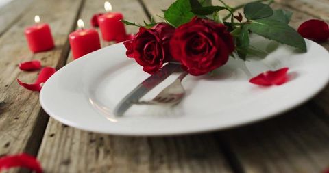 Romantic candlelit dinner featuring red roses on rustic wooden table