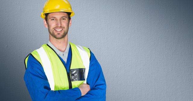 Portrait of construction worker standing with his arms crossed against grey background