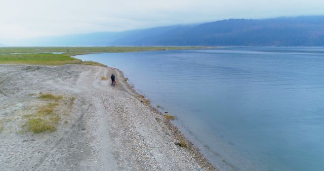 Solitary Figure Walking Along Tranquil Lakeshore in Misty Morning - Download Free Stock Photos Pikwizard.com