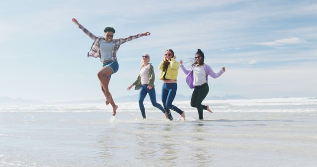 Happy group of diverse female friends having fun, dancing and smiling at the beach. holiday, freedom and leisure time outdoors.