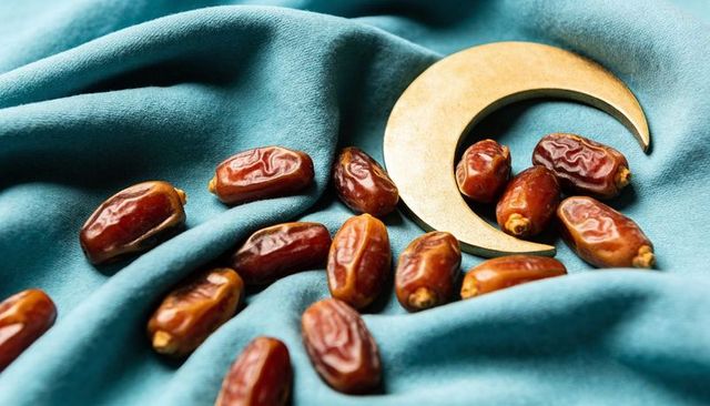 Golden crescent and medjool dates on teal velvet celebrating ramadan eid festive mood
