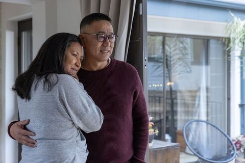 Senior Couple Sharing Intimate Moment at Home by Glass Door