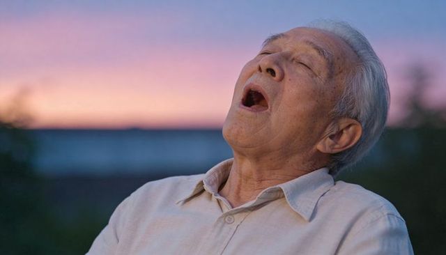 Senior asian man looking up and relaxing at sunset close-up headshot soft evening light