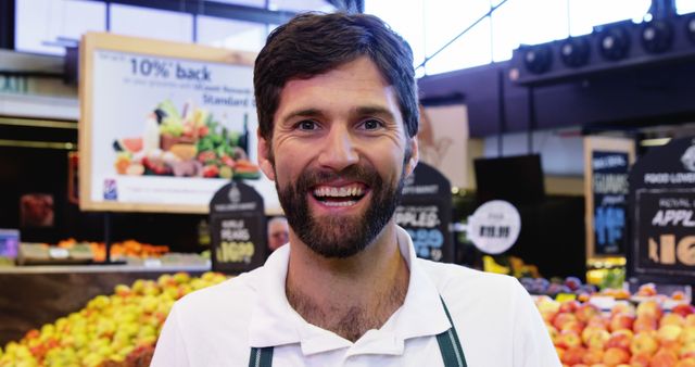 Smiling fruit market worker in front of colorful produce display - Download Free Stock Images Pikwizard.com