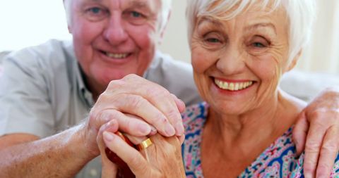 Happy Elderly Couple Holding Hands in Home Living Room
