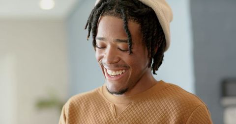 African American man smiling with eyes closed wearing beanie and quilted sweater