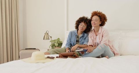 Friends Packing for Vacation on Bed Holding Passport and Boarding Pass