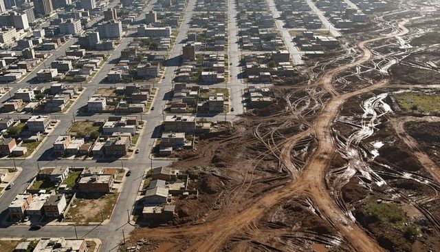 Aerial grid neighborhood showing paved streets meeting muddy construction ruts and lots