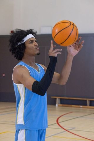 African American Athlete Spinning Basketball in Gym for Fitness