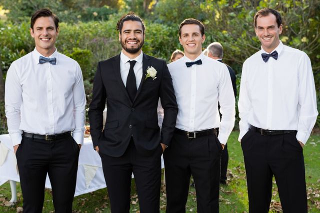 Portrait of smiling groom and groomsmen standing with hands in pocket