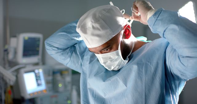 Biracial male surgeon wearing face mask and medical gloves in operating room. Medicine, healthcare, surgery and hospital, unaltered.