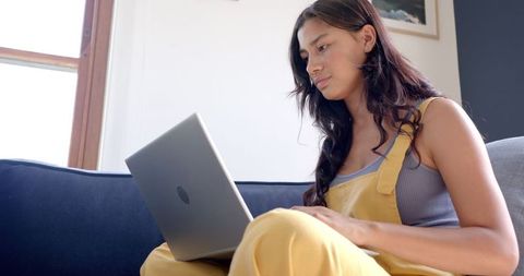 Teen Girl in Yellow Overalls Using Laptop on Couch