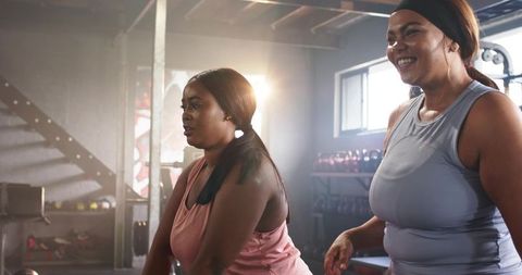 Diverse women training together in industrial gym, leaning and catching breath post-workout
