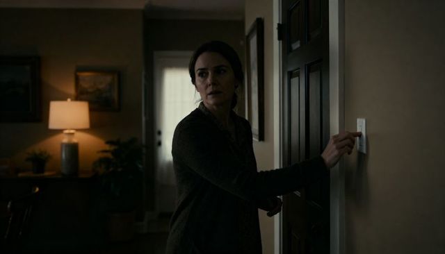 Woman pressing light switch in dim hallway turning off lights during tense home moment